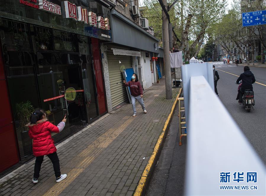 4月1日，在一元路上，人们在一家店铺前打羽毛球。 随着疫情防控形势好转，遛狗、锻炼身体、吃热干面、到江边散步……这些武汉人的生活日常正在逐渐恢复，人们熟悉的生活已经在回来的路上。 新华社记者肖艺九摄