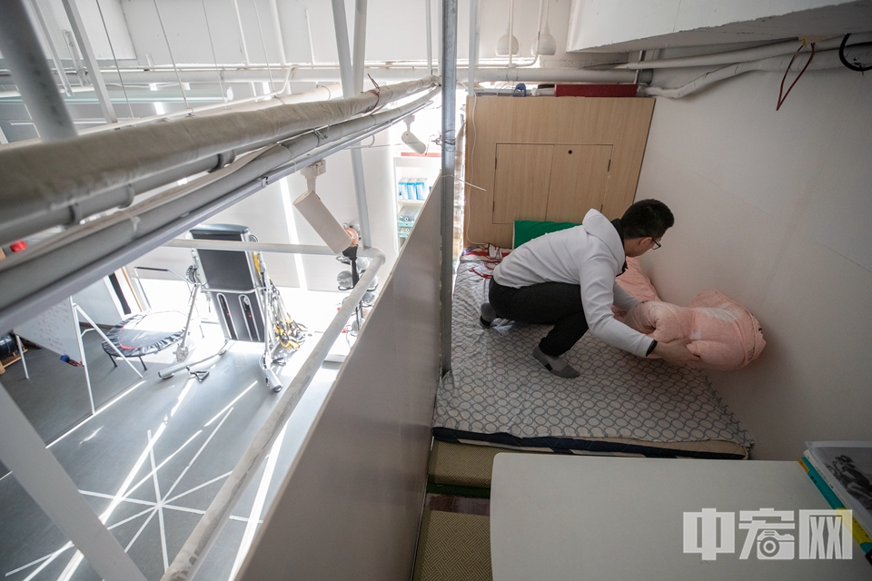 李磊住的地方就在健身教室内，他将摆放健身器材的架子上方围起，铺上被褥，简易生活区就布置好了。 中宏网记者 富宇 摄