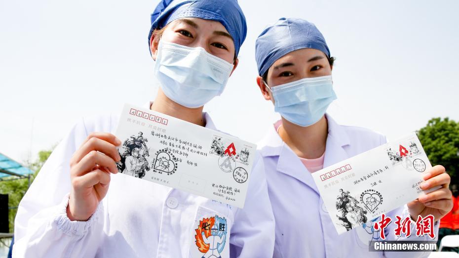 5月11日，中国邮政特别发行的《众志成城 抗击疫情》邮票首发式在湖北武汉举行。来自武汉协和医院、同济医院中法新城院区、武汉肺科医院、金银潭医院等6所医院的66名医护人员代表参加首发式并接受了赠送的邮品。图为医护人员展示邮品。 中新社记者 张畅 摄