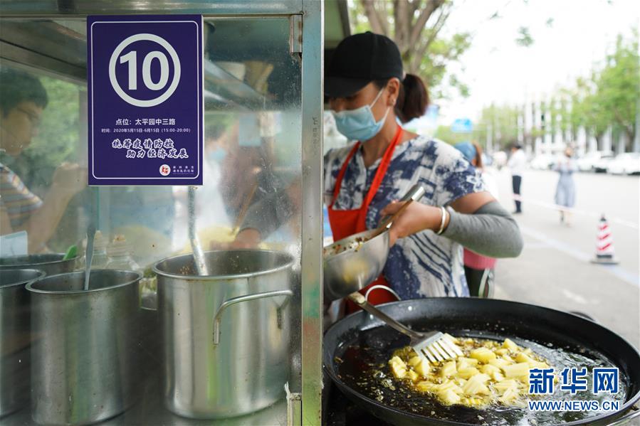 6月2日，商家在成都市太平园中三路临时占道摊点上准备食品。  新华社发（胥冰洁摄）