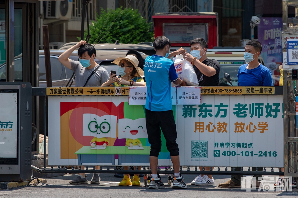 6月18日，北京西城区广外街道一小区，被封闭在社区内的市民隔着护栏拿取外卖商品。据悉，自6月16日凌晨2时起，西城区对广外天陶红莲市场周边7个社区实施封闭式管理，严控人员出入。中宏网记者 康书源 摄