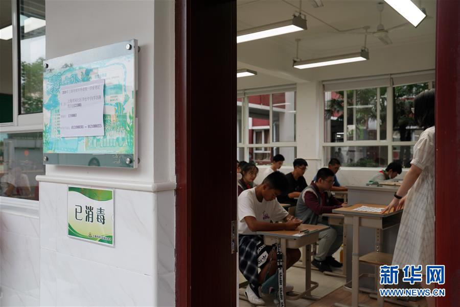 6月27日，在上海市闵行区莘松中学考点，考生在考场内等待开考。按照规定，考生进出考点和考场时须佩戴口罩，就座后可不用佩戴口罩。 当日，2020年上海市初中毕业统一学业考试开考。上海市各考点落实多项措施，筑牢防疫“安全墙”。考生需提前签署《考生考试安全承诺书》，进出考点考场须佩戴口罩，并接受防疫安全检查。 新华社记者 刘颖 摄