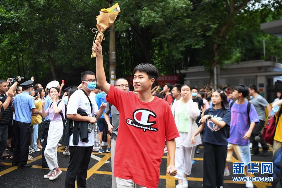 7月8日，考生拿着鲜花向湖南省长沙市一中考点外等候的家长示意。 当日，全国部分地区2020年高考结束。 新华社记者 薛宇舸 摄