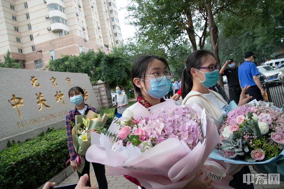 7月10日，北京中关村中学，考生们纷纷手捧鲜花在学校前留影。中宏网记者 康书源 摄