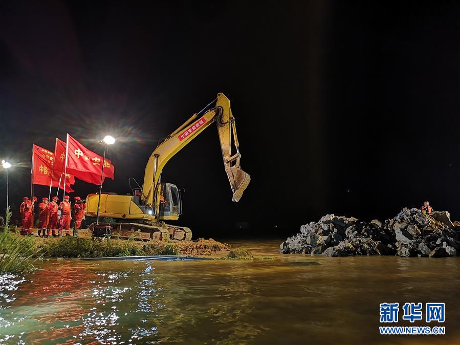 中国安能第二工程局的工作人员对问桂道圩决口进行封堵（7月13日摄）。 7月13日23时8分，随着操作手驾驶推土机将最后一车土石倒入决口处，江西省鄱阳县问桂道圩决口封堵现场响起一片欢呼声。在抢险人员连续奋战83小时后，127米宽的决口成功合龙。 新华社发（中国安能第二工程局供图）