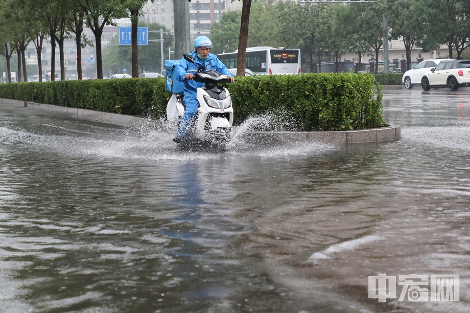 外卖小哥为雨中出行不便的市民送去餐食。 中宏网记者 富宇 摄