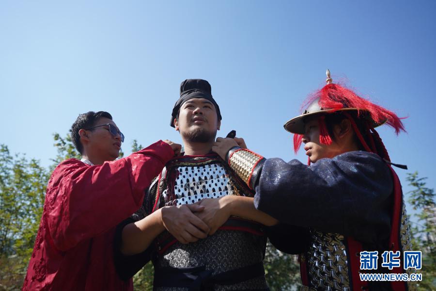 “虔州武备司”成员曾繁强（左）、黄正源（右）帮宋昊穿上唐代铠甲。新华社记者 周密 摄