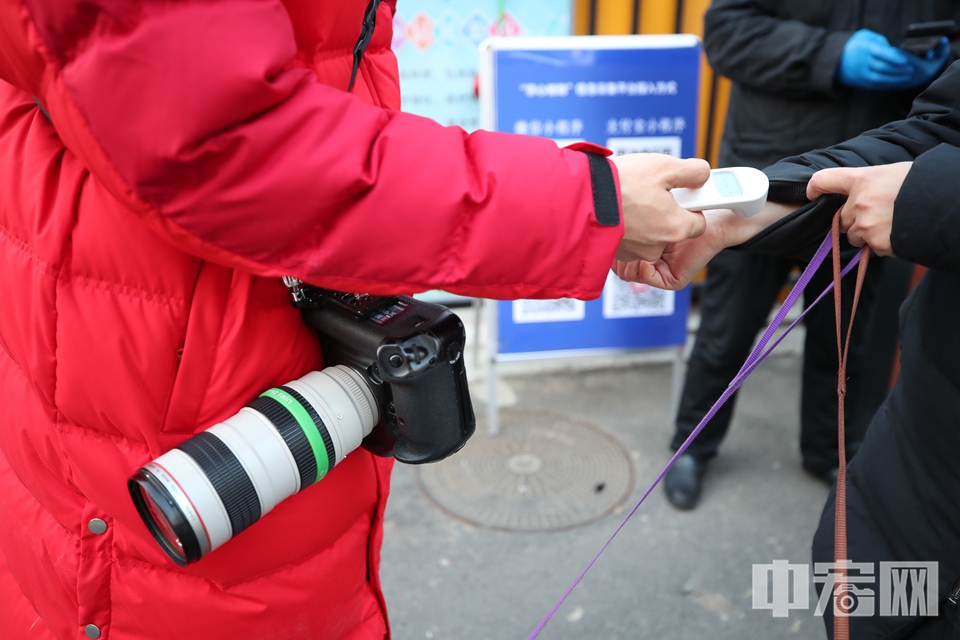 2020年2月25日，志愿者陈硕在北京月坛街道某小区为居民测量体温，除了志愿者，他还有另一个身份——一名摄影记者。 中宏网记者 富宇 摄
