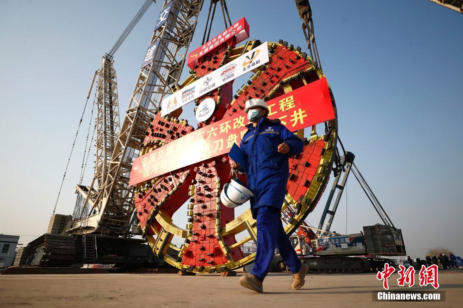 1月20日，施工人员从“运河号”盾构机刀盘前经过。当日，北京东六环改造工程再有新进展，中国国产最大直径盾构机“运河号”刀盘成功下井。标志着东六环改造工程两台直径16.07米超大直径盾构机平行组装下井工作顺利完成，将一先一后从隧道北端出发，下穿运潮减河、地铁6号线、北运河、城市副中心火车站等重要建筑及河流后，到达盾构隧道最南端。北京东六环入地改造工程项目全长16公里，入地改造公里隧道总长9.2公里。预计东六环入地改造工程于2023年底完工。 中新社记者 富田 摄