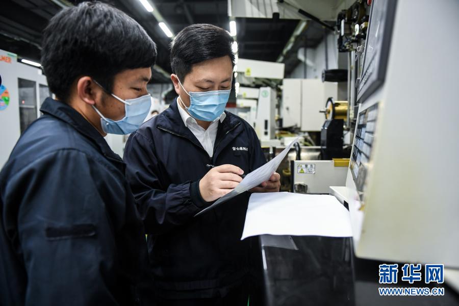 2月25日，在深圳富士康科技集团龙华科技园，杨飞飞（右）与产业工人交流。新华社记者 毛思倩 摄