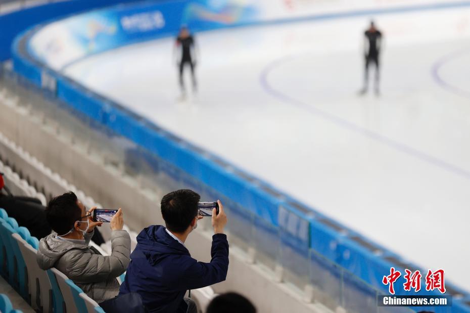 4月7日，“相约北京”冰上项目测试活动速度滑冰比赛在北京国家速滑馆拉开帷幕。图为观众拍摄选手热身。 中新社记者 韩海丹 摄
