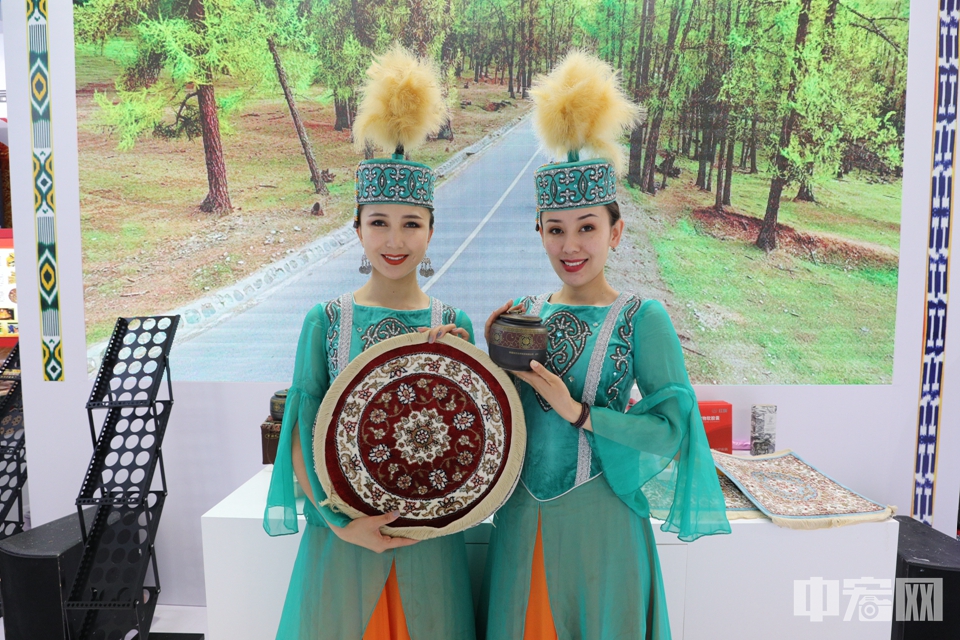 身着少数民族服饰的工作人员展示新疆礼物。