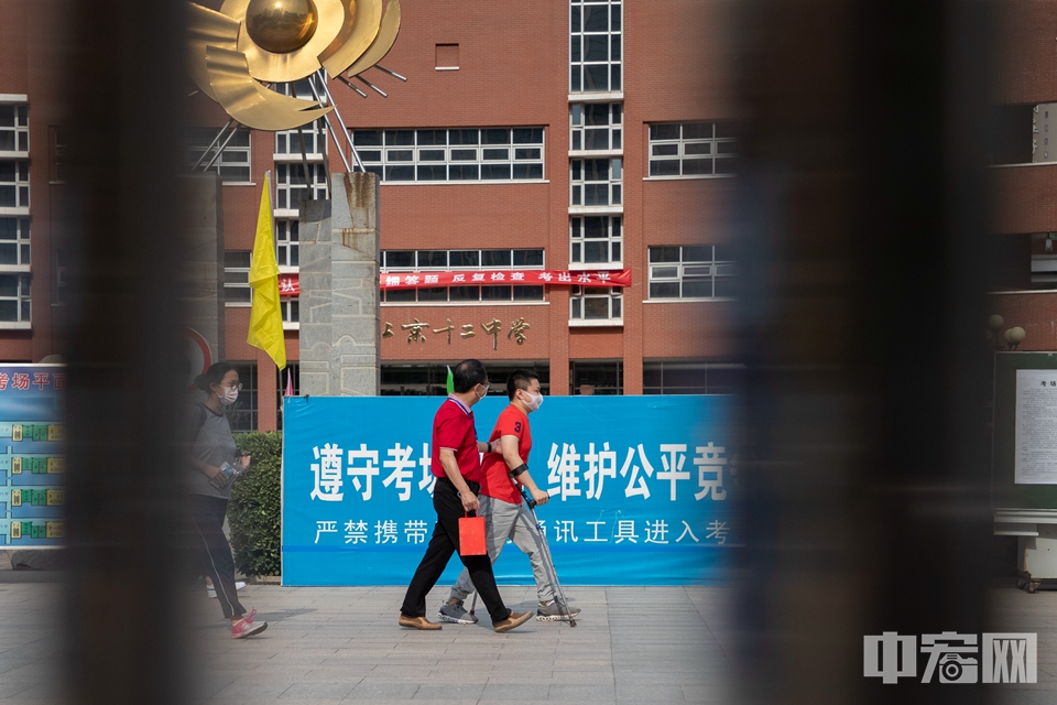6月7日，北京市第十二中学考点，一名腿部受伤的考生在老师的陪同下走进考场。