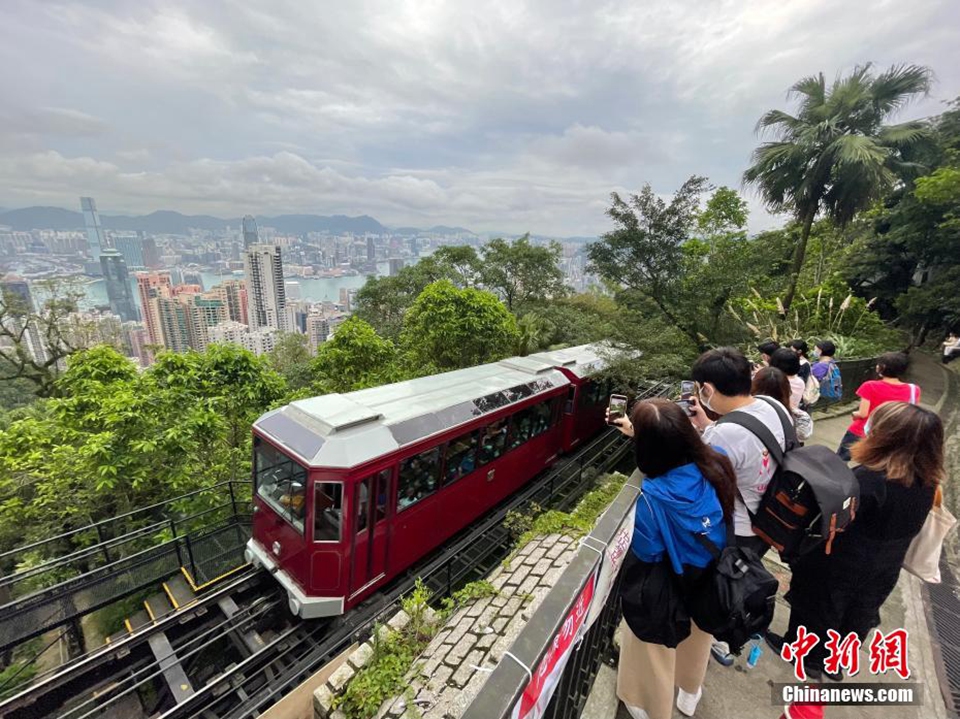 6月25日,香港山頂纜車於樹林中穿梭,乘客飽覽維港兩岸高樓大廈景色.