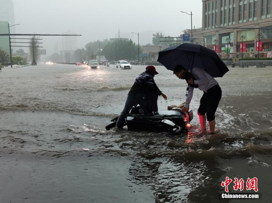 7月20日，市民一同扶起被雨水冲倒的电动车。中新社记者 韩章云 摄