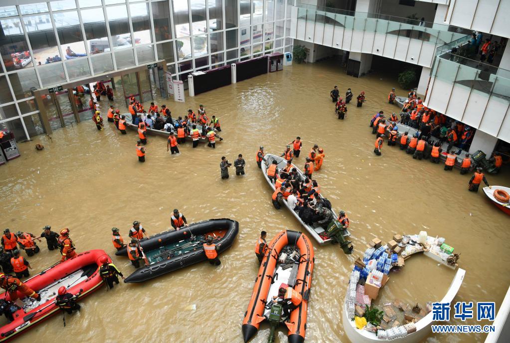 7月22日，在阜外华中心血管病医院门诊部，救援人员在积水的大厅内驾驶舟艇转移病患。