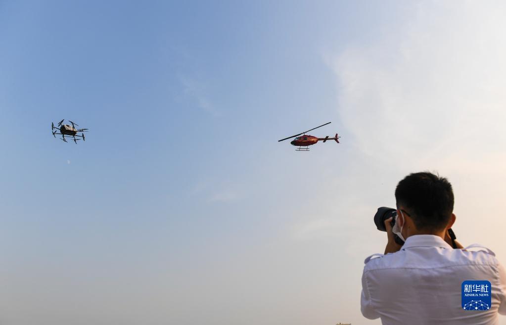 9月15日，在深圳市盐田区的东部通航运行基地，一架贝尔206直升机（右）与一台亿航载人级自动驾驶飞行器在同一空域中进行试飞。新华社记者 毛思倩 摄