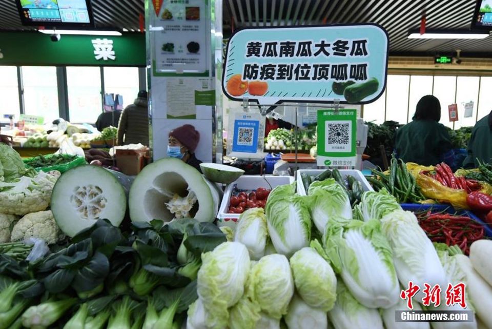 图为一蔬菜摊位上摆放着“黄瓜南瓜大冬瓜，防疫到位顶呱呱”的标语。 王刚 摄