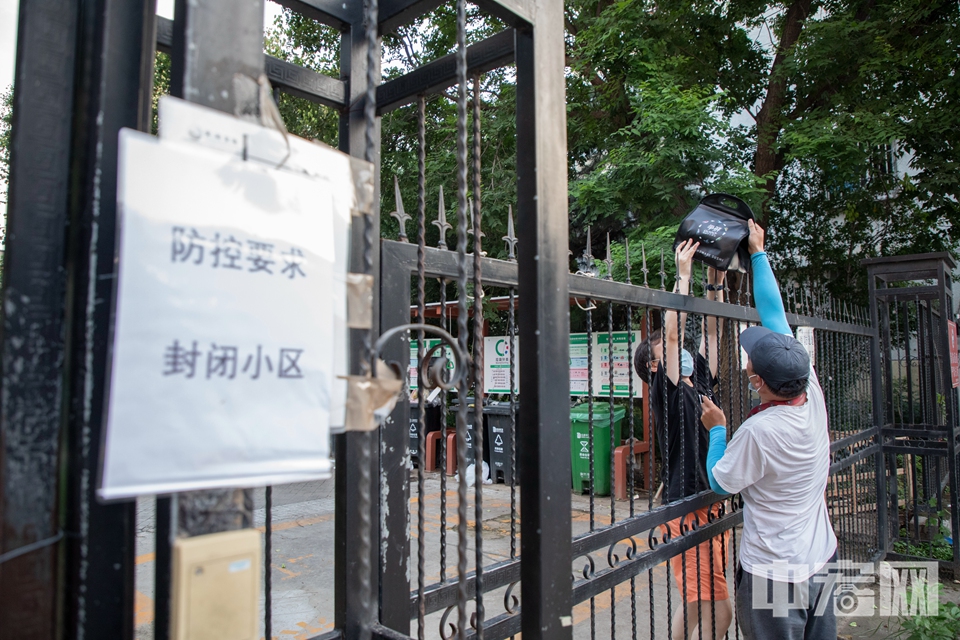 7月31日，北京回龙观地区，龙锦苑六区封闭管理中的市民通过小区围栏取外卖。7月29日，北京新增新冠肺炎确诊病例，其居住的小区及周边八个小区实施14天居家隔离观察封闭管理。 中宏网记者 康书源 摄