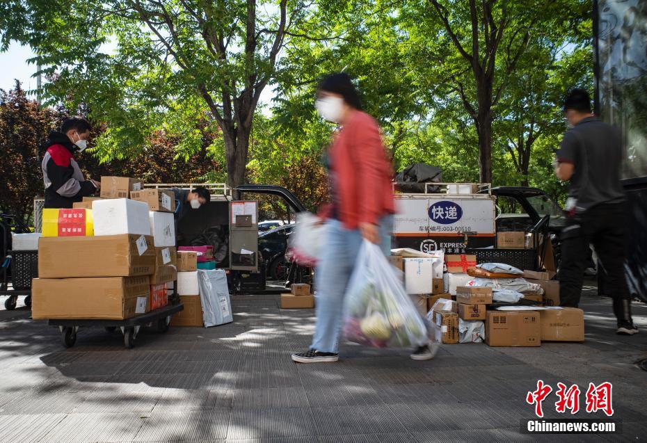 5月13日上午，快递员在北京市朝阳区望京街道的一个居民小区外整理快件，准备送往各家各户。中新社记者 侯宇 摄