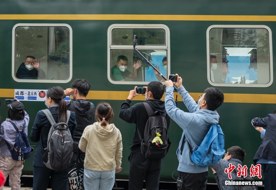 四川成都,開往北京西的列車駛出成都站,旅客揮手與站臺上的人們告別