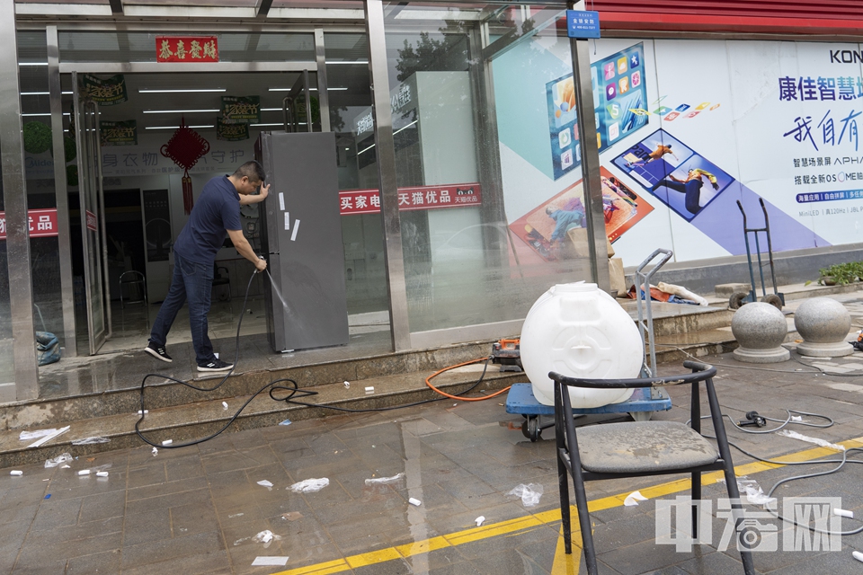 华阳路上一家电器店门口，工作人员正在清洗被水淹的电器。 中宏网记者 康书源 摄