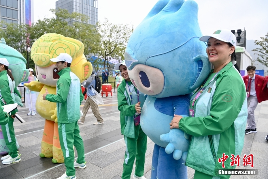 9月22日，浙江杭州，杭州第19届亚运会运动员村内举行代表团欢迎仪式，欢迎入住运动员村的代表团。图为土库曼斯坦代表团成员与吉祥物合影留念。中新社记者 王东明 摄