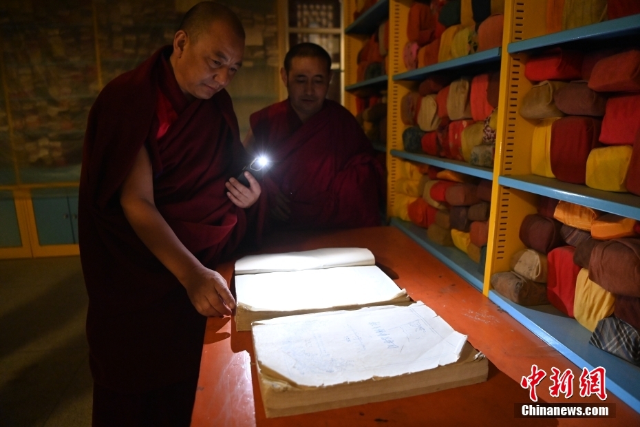 享誉“世界藏学府”的拉卜楞寺，其数字化进程近年来备受关注。拉卜楞寺文物管理委员会成员更登丹巴2月5日接受中新社记者采访时表示，目前正在为库存6.8万余函古籍善本“编纂目录、建档归案”，为数字化文物保护奠定基础。图为2月1日，甘肃省甘南藏族自治州夏河县拉卜楞寺，更登丹巴（左）在藏经楼查看首次系统整理编制的《拉卜楞寺总书目》。中新社记者 九美旦增 摄
