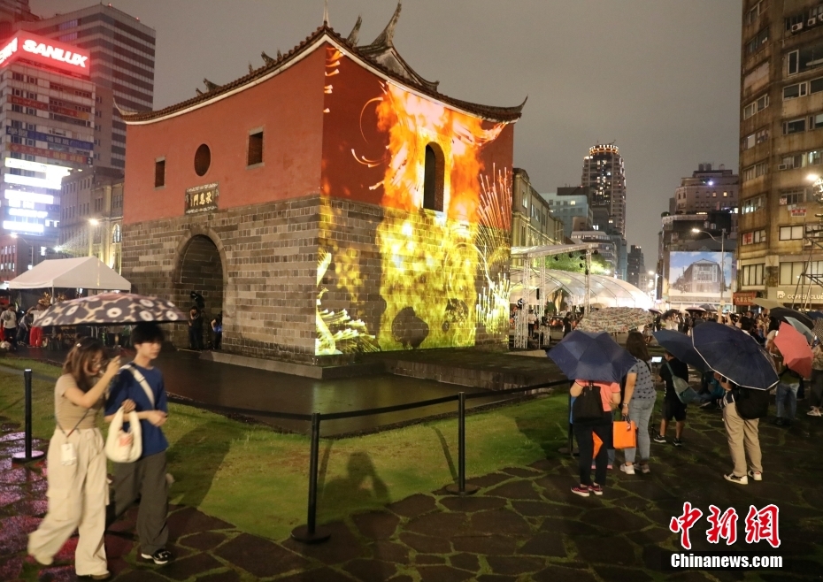 4月27日，台北建城140周年系列活动在台北市北门广场开幕。图为市民在雨中观赏投映在保留原貌的台北北门的光雕秀。中新社记者 刘舒凌 摄