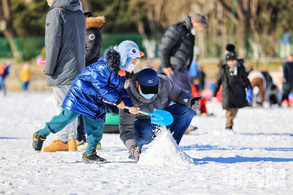 小朋友在龍?zhí)侗┕?jié)上玩雪。