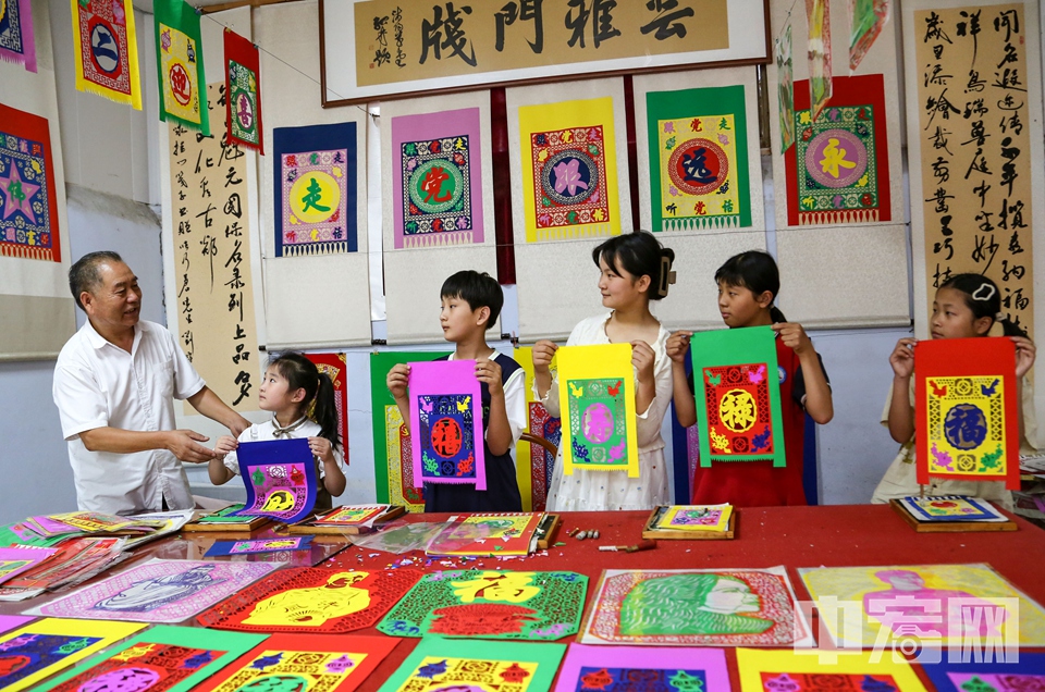 孩子們向張乃蒼展示制作的掛門箋。 李結義 攝