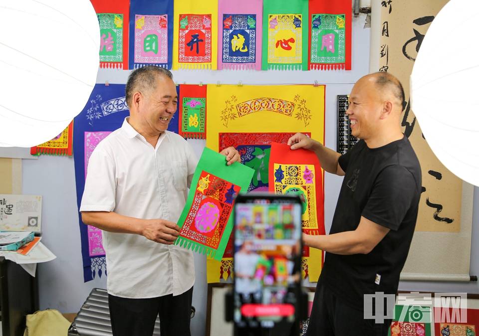 6月14日，在山東省臨沂市郯城縣馬頭鎮(zhèn)萬(wàn)高冊(cè)村，村支書張立和張乃蒼一起直播銷售掛門箋。 李結(jié)義 攝